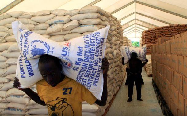 Pessoas carregam sacos de alimentos do Programa Mundial de Alimentos da ONU em assentamento para refugiados do Sudão do Sul em Uganda