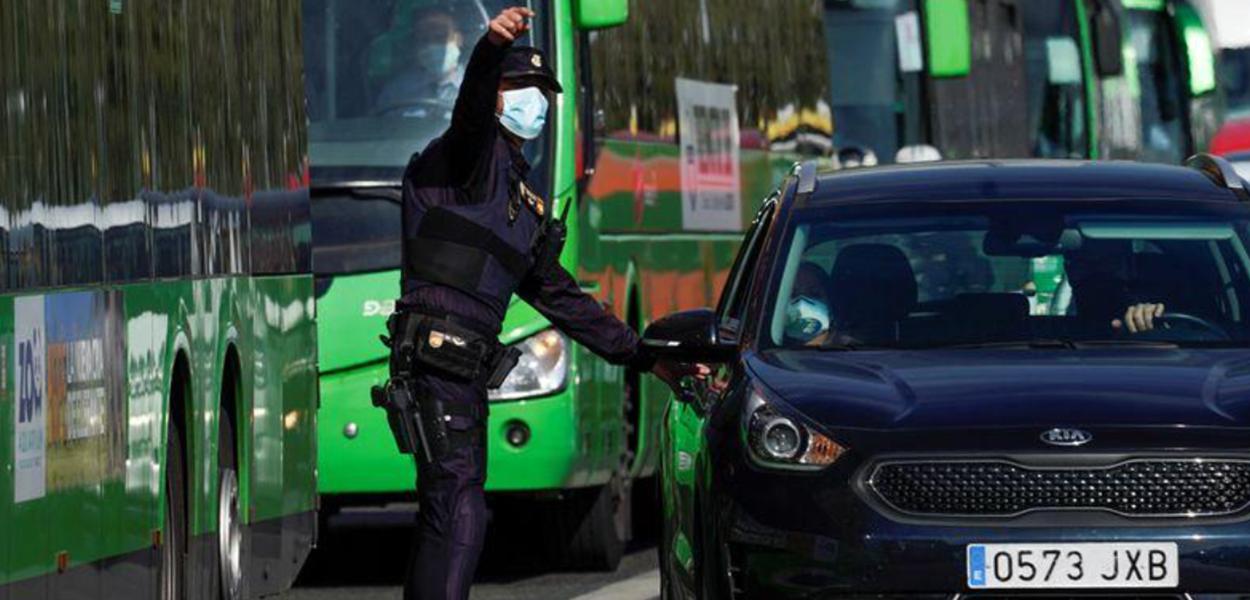 Policial espanhol conversa com pessoas em um carro em um dos postos de controle em meio a um lockdown parcial em Madri