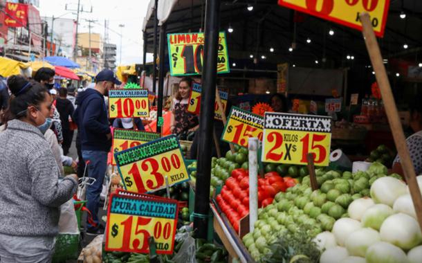 Pessoas olham cartazes com preços de produtos do lado de fora de um mercado conhecido como La Merced, na Cidade do México