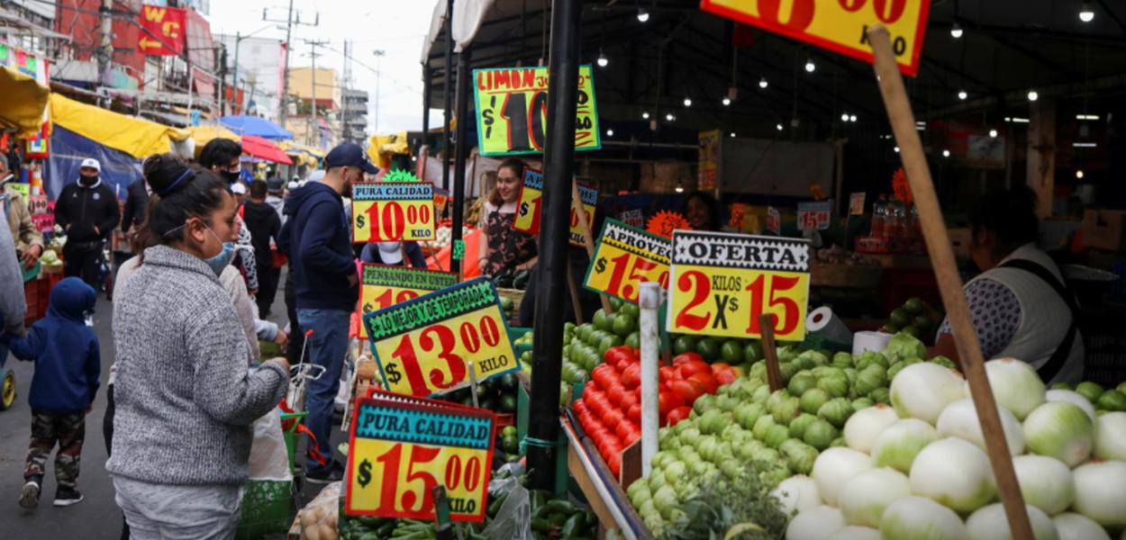 Pessoas olham cartazes com preços de produtos do lado de fora de um mercado conhecido como La Merced, na Cidade do México