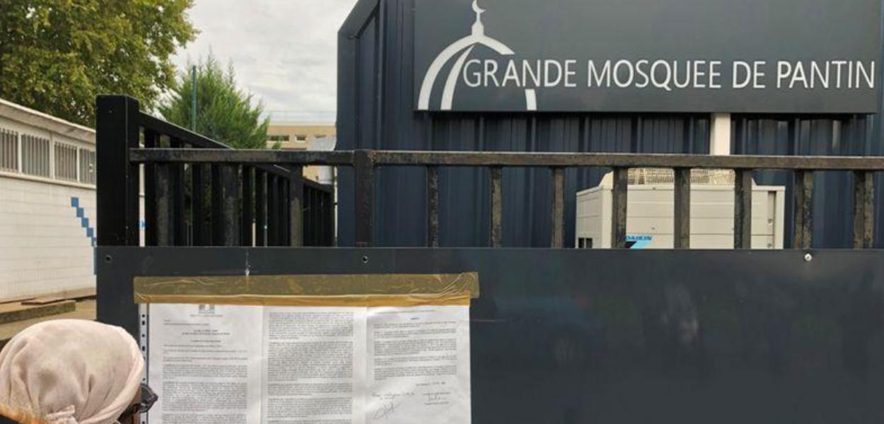 Mulher lê decreto na entrada da Grande Mesquista de Pantin