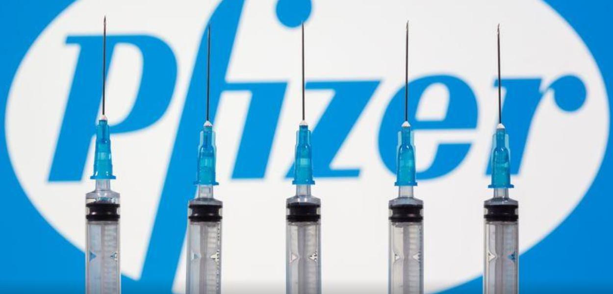 Seringas em frente ao logo da Pfizer