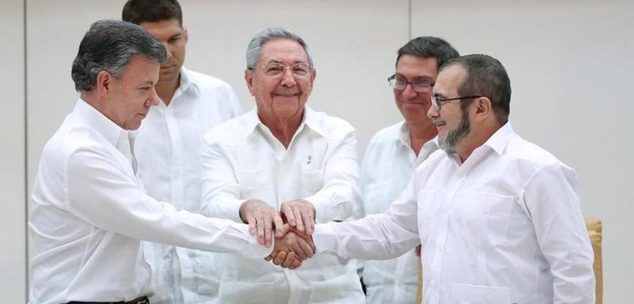 O ex-presidente Juan Manuel Santos cumprimenta o líder das FARC, Lodoño; ao centro, o ex-presidente de Cuba, Raúl Castro