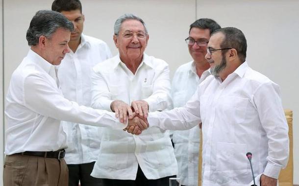 O ex-presidente Juan Manuel Santos cumprimenta o líder das FARC, Lodoño; ao centro, o ex-presidente de Cuba, Raúl Castro