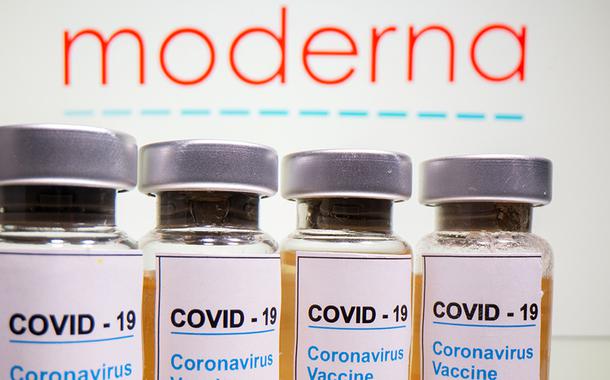 Frascos rotulados como de vacina contra Covid-19 em frente a logo da Moderna em foto de ilustração