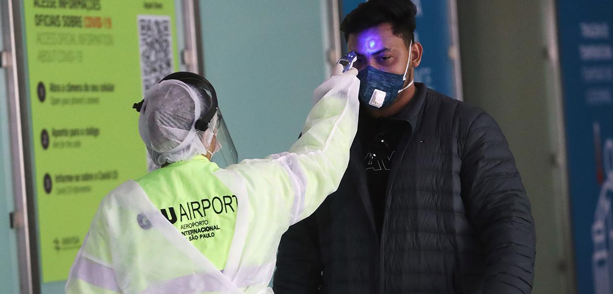 Funcionária checa temperatura de passageiro no aeroporto de Guarulhos