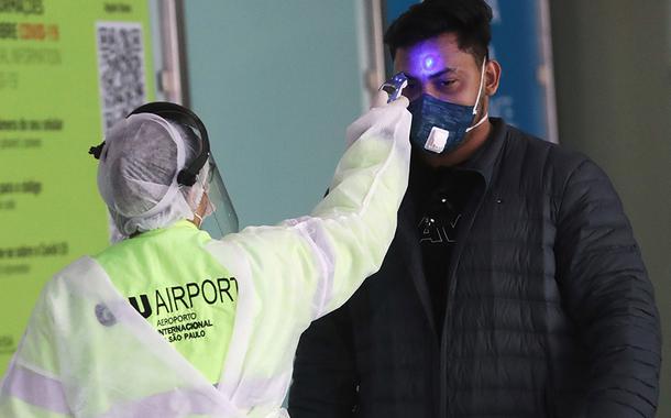 Funcionária checa temperatura de passageiro no aeroporto de Guarulhos