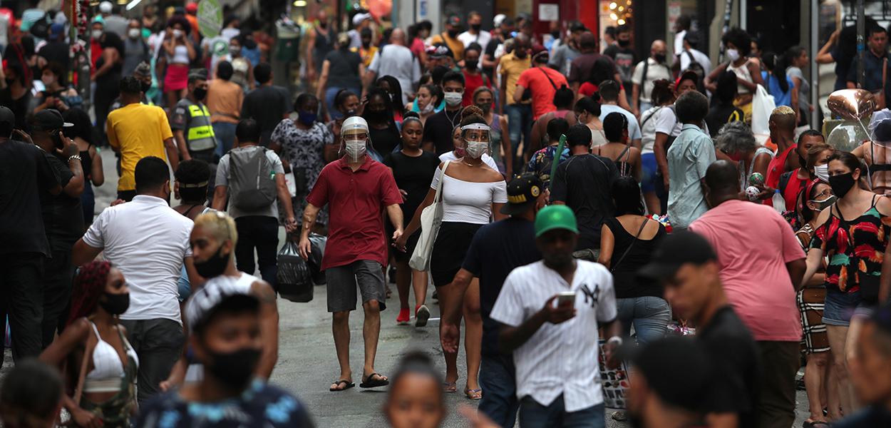 Pessoas caminham por rua de comércio popular no centro de São Paulo