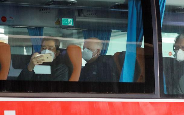 Membros da equipe da Organização Mundial da Saúde (OMS) encarregada de investigar as origens da pandemia do coronavírus sentam em um ônibus antes de deixar aeroporto de Wuhan.