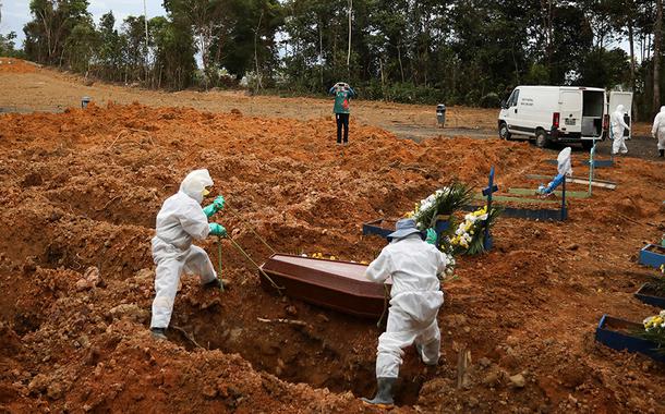 Coveiros vestindo roupas de proteção se preparam para enterrar no cemitério Parque Taruma, em Manaus.