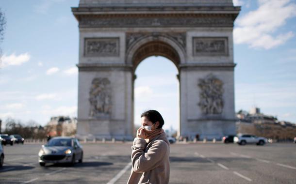 Uma mulher usando uma máscara protetora caminha perto do Arco do Triunfo enquanto a França enfrenta um surto de doença por coronavírus, em Paris