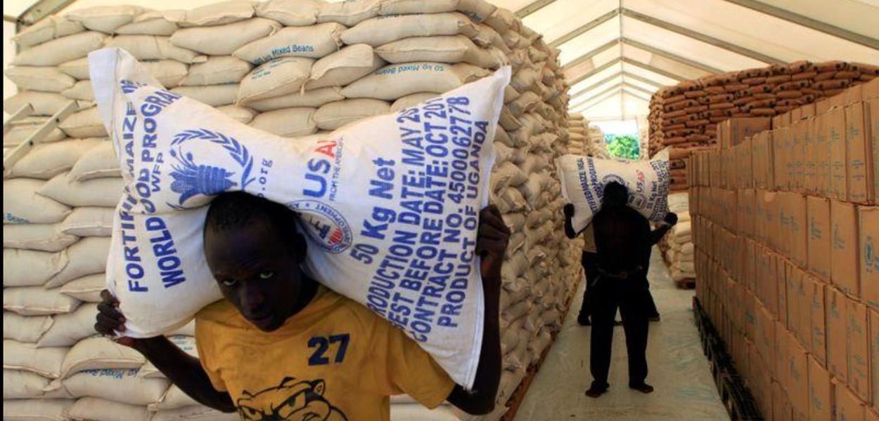 Pessoas carregam sacos de alimentos do Programa Mundial de Alimentos da ONU em assentamento para refugiados do Sudão do Sul em Uganda