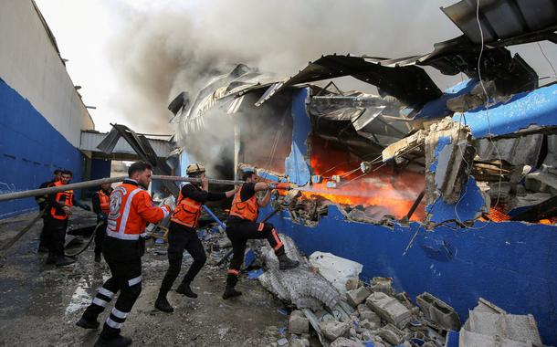 Bombeiros palestinos apagam chamas de fábrica atingida por míssil de Israel