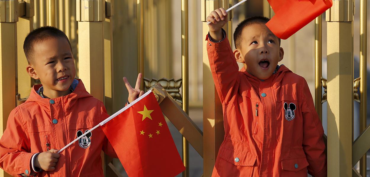 Gêmeos chineses com bandeira do país em praça de Pequimung-Hoon