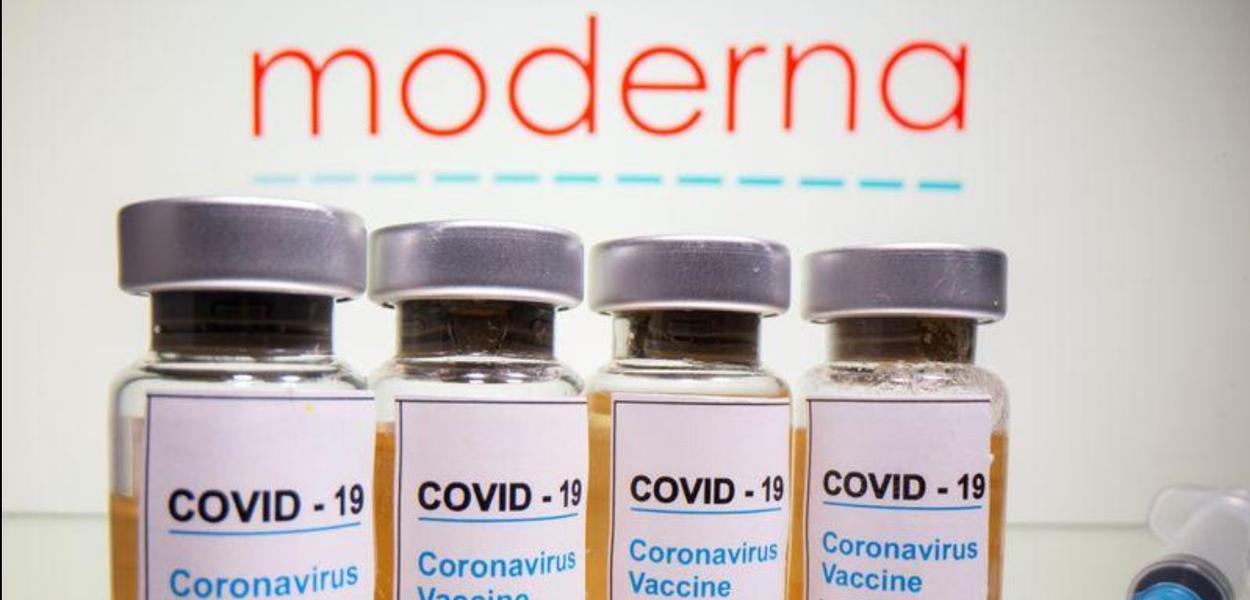 Frascos rotulados como de vacina contra Covid-19 em frente ao logo da Moderna