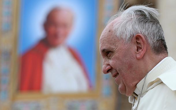 Papa Francisco passa ao lado de uma tapeçaria do falecido Papa João Paulo II, no Vaticano