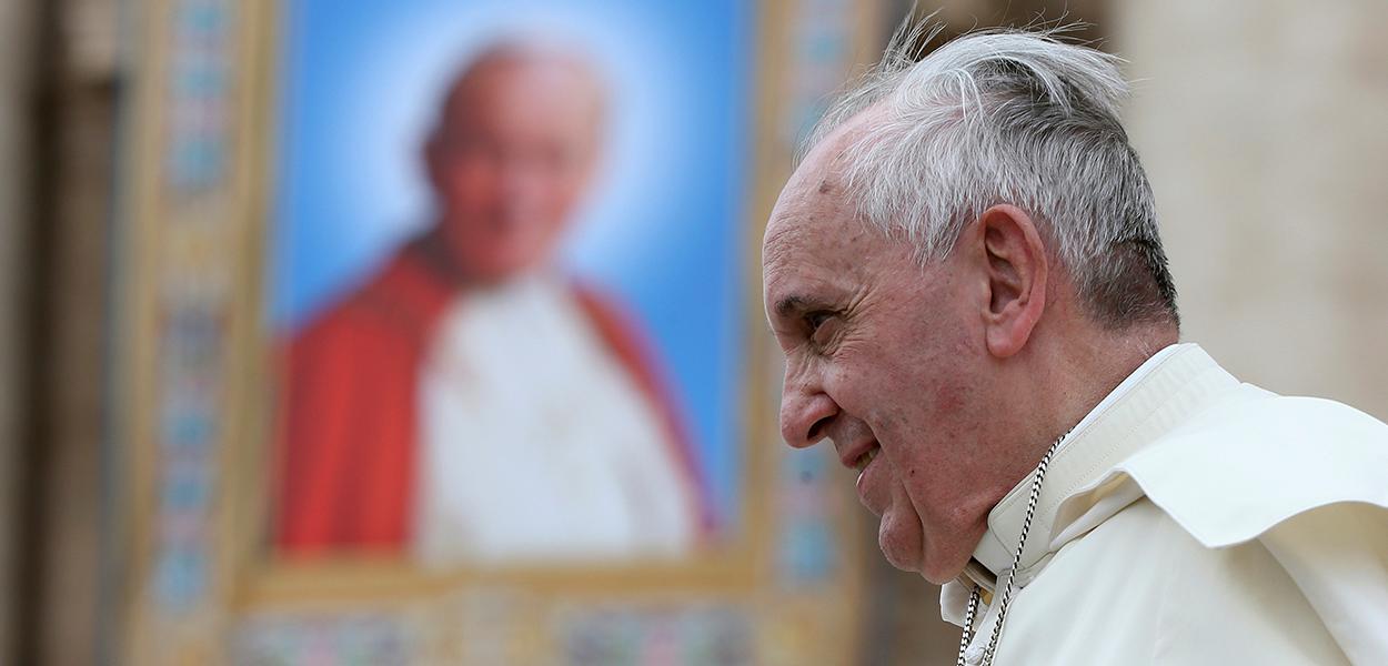 Papa Francisco passa ao lado de uma tapeçaria do falecido Papa João Paulo II, no Vaticano