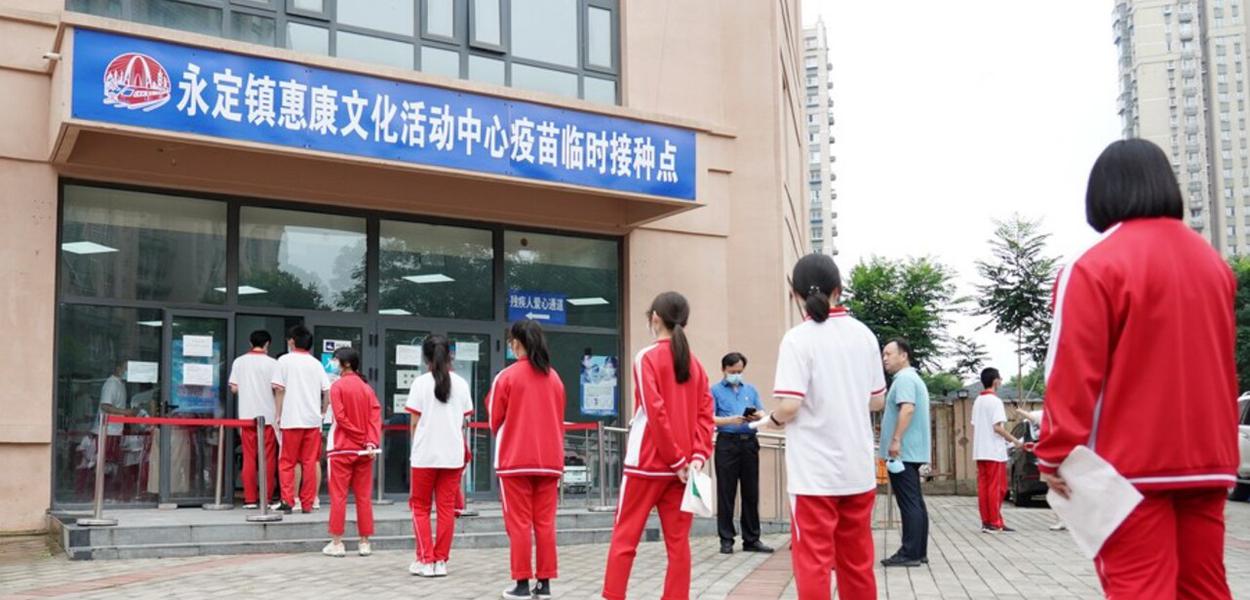 Estudantes chineses em fila diante de um posto de vacinação