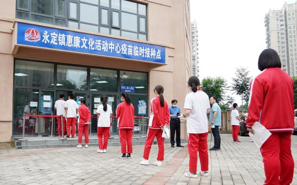 Estudantes chineses em fila diante de um posto de vacinação