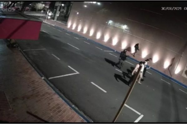 Dois homens armados conduzem uma fila com quatro reféns, alinhados lado a lado, por uma rua de Araçatuba.