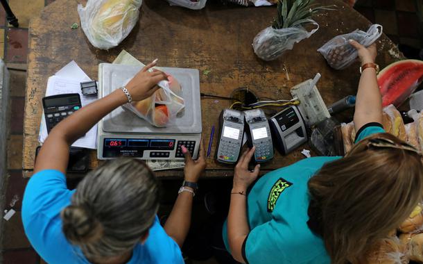 Funcionários pesam frutas em mercado de Caracas