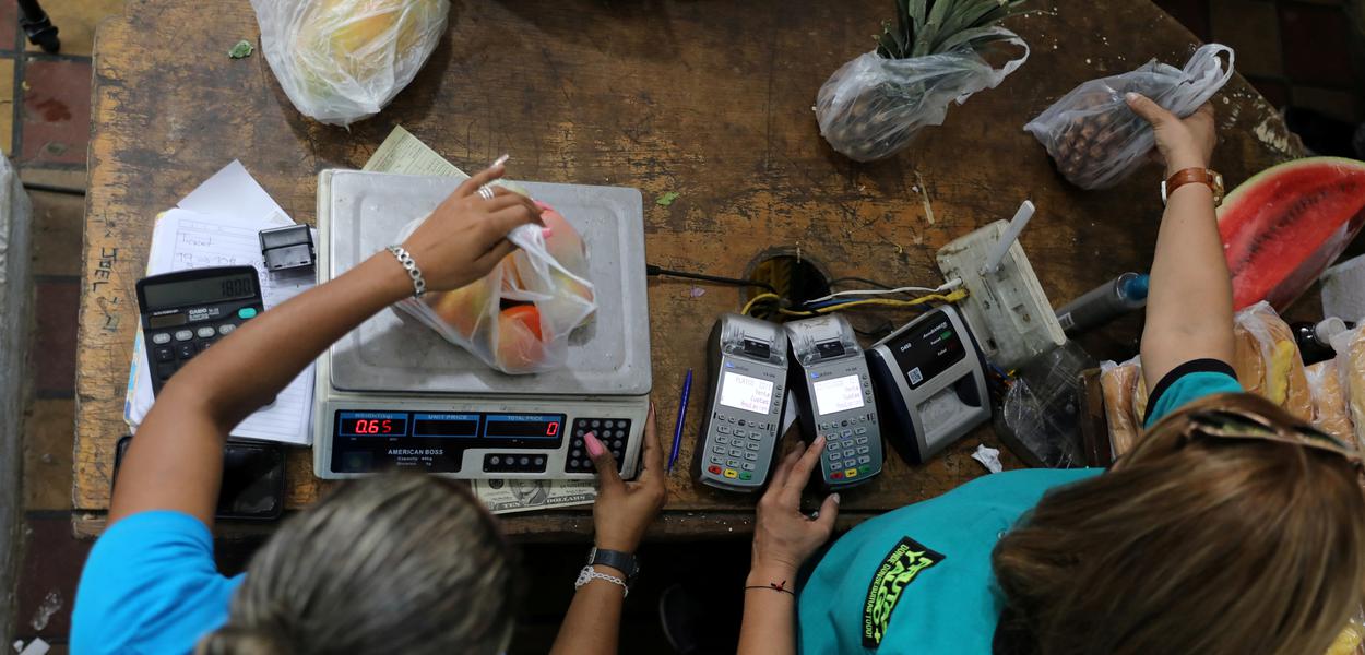 Funcionários pesam frutas em mercado de Caracas