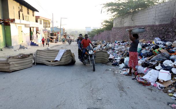 Pessoas passam por barricada em rua de Porto Príncipe, no Haiti