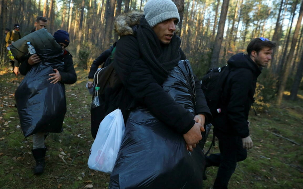 Migrantes sírios caminham depois de cruzar a fronteira entre os dois países, perto de Lewosze, na Polônia, em 29 de outubro de 2021