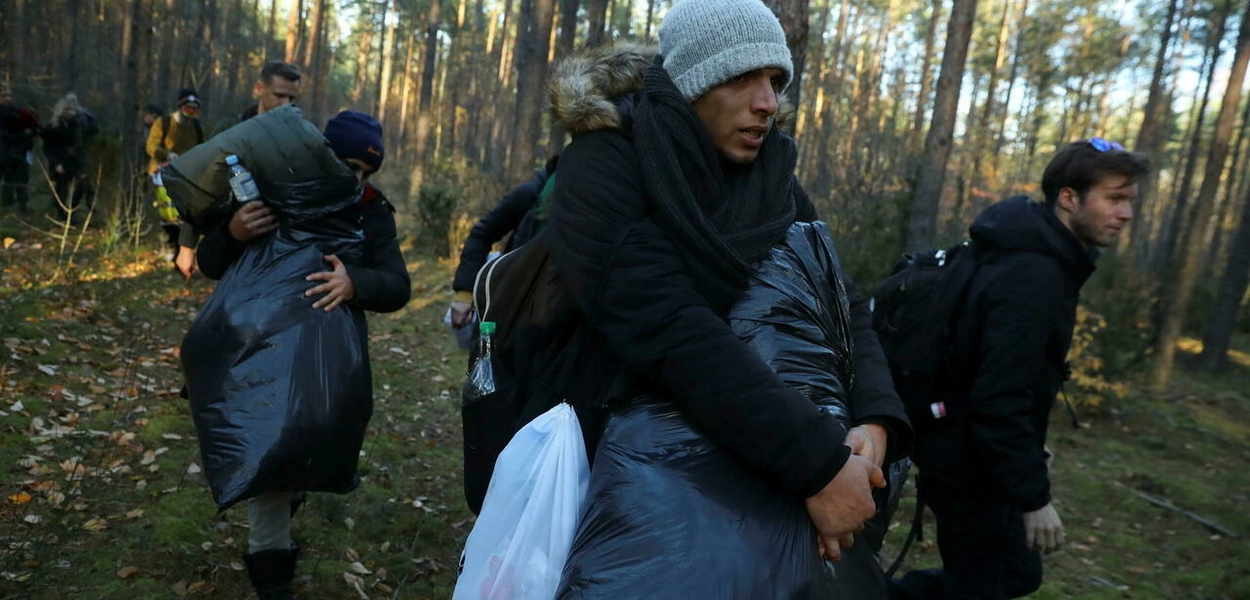 Migrantes sírios caminham depois de cruzar a fronteira entre os dois países, perto de Lewosze, na Polônia, em 29 de outubro de 2021