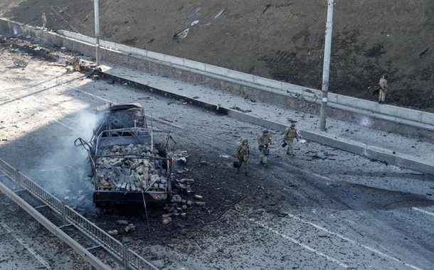 Militares ucranianos passam por um veículo danificado, no local de um combate com tropas russas em Kiev, Ucrânia, em 26 de fevereiro