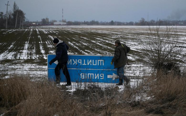 Membros das Forças de Defesa Territoriais da Ucrânia escondem uma placa de trânsito que impede a navegação do exército russo na região de Kiev, Ucrânia, em 8 de março de 2022