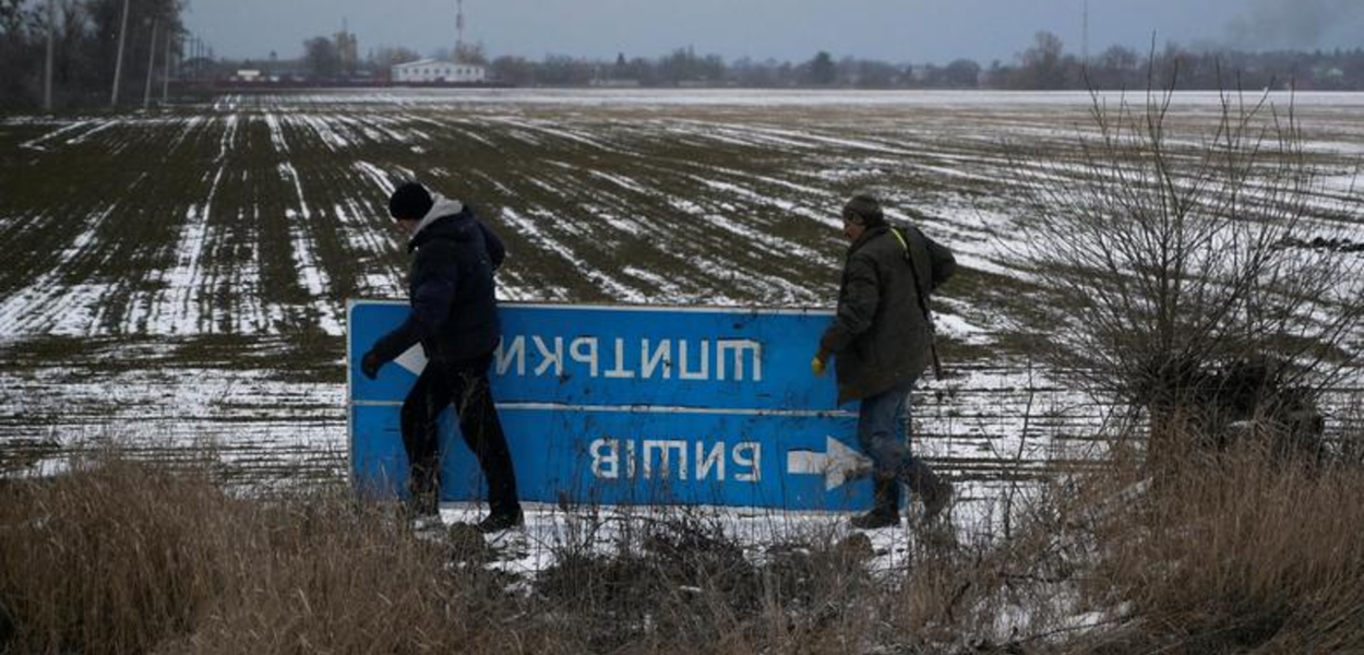 Membros das Forças de Defesa Territoriais da Ucrânia escondem uma placa de trânsito que impede a navegação do exército russo na região de Kiev, Ucrânia, em 8 de março de 2022