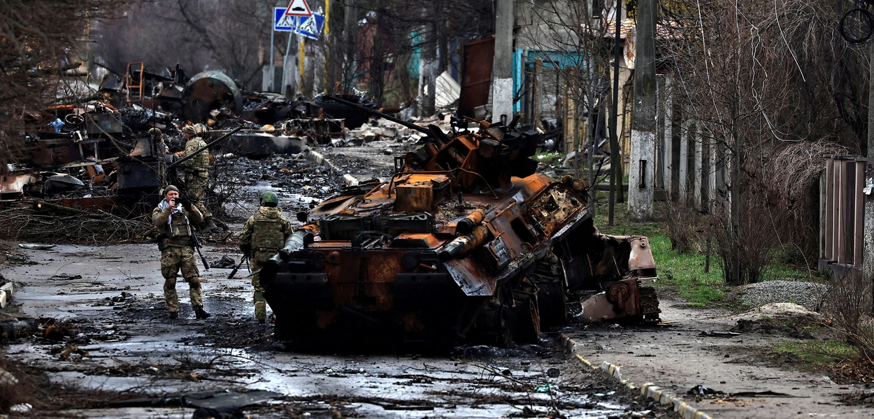 Um soldado tira uma foto de seu companheiro enquanto ele posa ao lado de um tanque russo destruído e veículos blindados, em meio à invasão da Rússia na Ucrânia em Bucha, na região de Kiev, Ucrânia 2 de abril de 2022