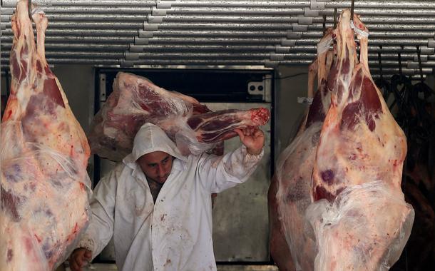 Trabalhador descarrega carne em açougue