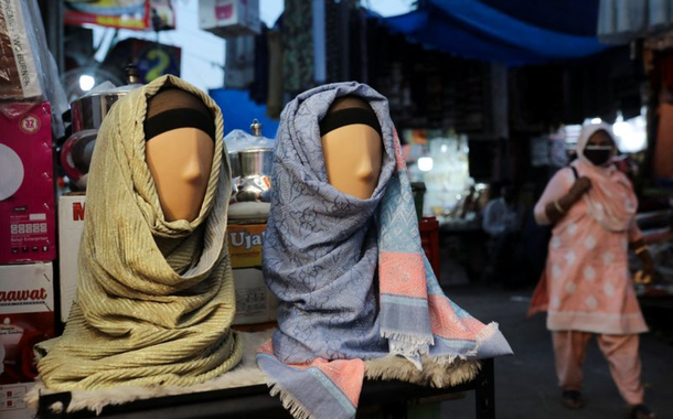 Mulher passa por manequins com hijabs em loja de Nova Délhi