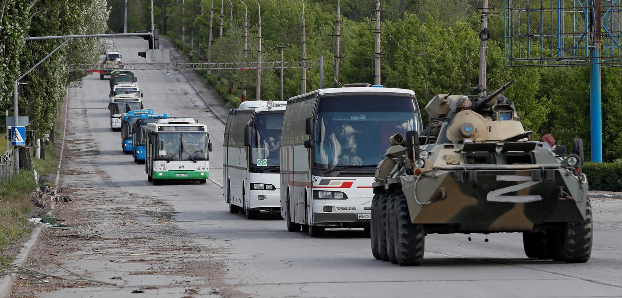 Ônibus transportando soldados ucranianos que se renderam na usina siderúrgica de Azovstal, em Mariupol, são escoltados por veículos blindados de tropas pró-Rússia