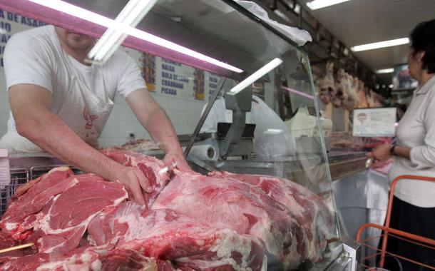 Funcionário carrega pedaços de carne em açougue de São Paulo