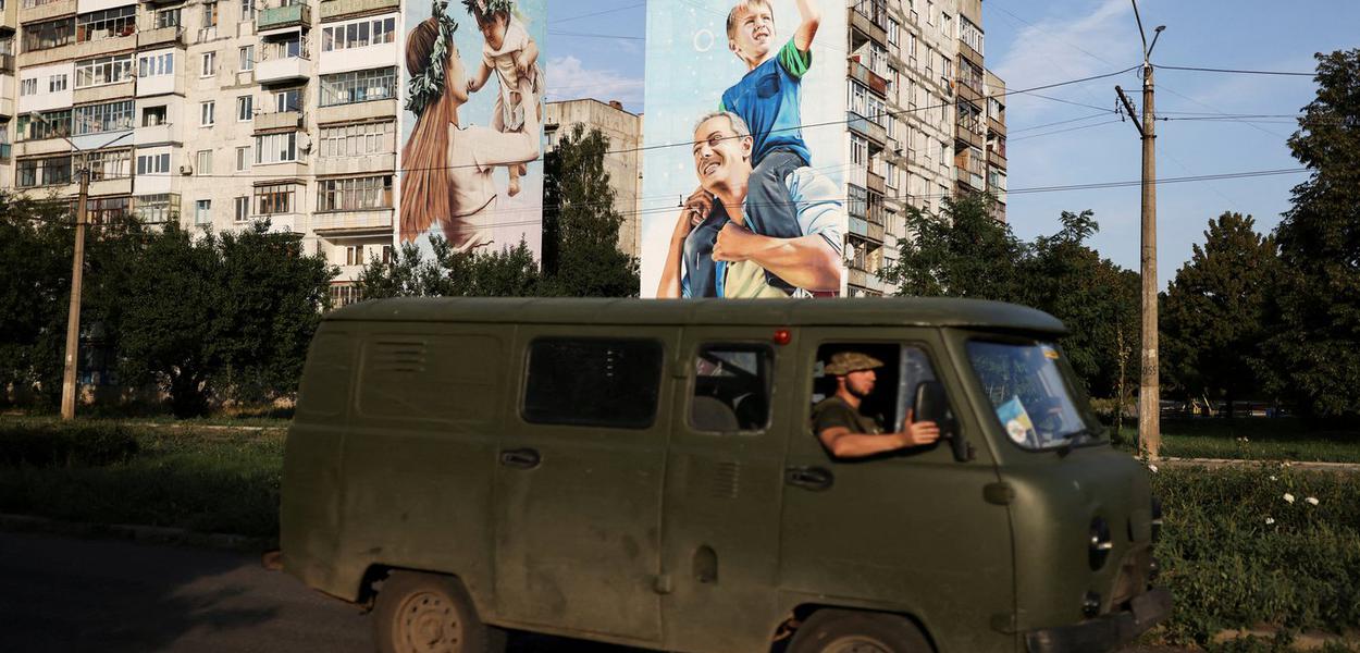 Militares ucranianos passam por edifício residencial danificado em Bakhmut, na região de Donetsk, no leste da Ucrânia 14/08/2022