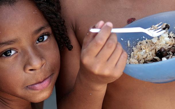 Thawanny Silva de Souza, de 6 anos, (E) e Rafael Silva de Souza, de 9 anos, (D), comem prato com arroz, feijão e ovo na Favela do Arci-Íris, em Recife