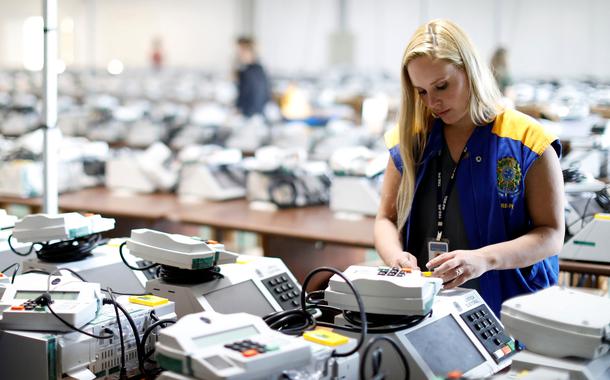 Funcionária da Justiça Eleitoral com urnas eletrônicas