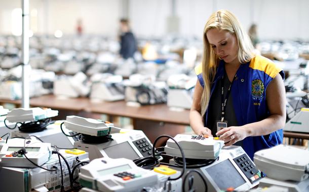 Funcionária da Justiça Eleitoral com urnas eletrônicas