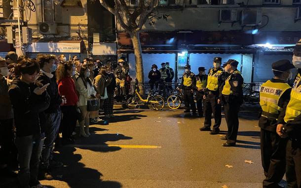Pessoas ficam em frente a uma fila de policiais durante uma manifestação contra as restrições do COVID-19