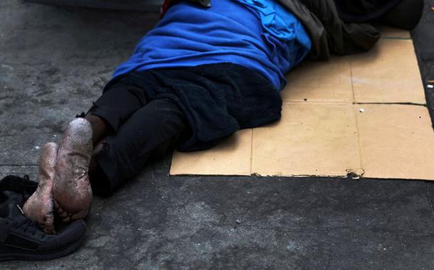 Um homem dorme em uma caixa de papelão ao longo da rua 34, perto da Estação Pensilvânia, em Nova York, EUA