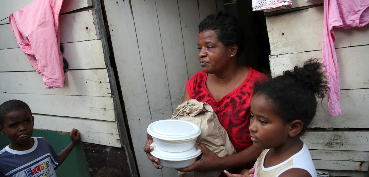 Residentes de uma comunidade no Rio de Janeiro recebem comida de voluntários