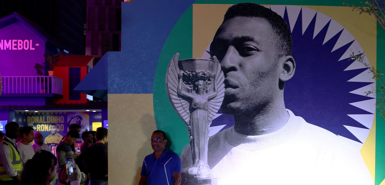 Torcedor em frente a foto de Pelé em exposição da Conmebol na Copa do Mundo do Catar