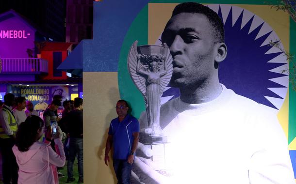 Torcedor em frente a foto de Pelé em exposição da Conmebol na Copa do Mundo do Catar