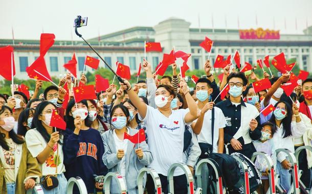 Patriotas chineses favoráveis ao governo comunista em cerimônia de hasteamento da bandeira na Praça da Paz Celestial