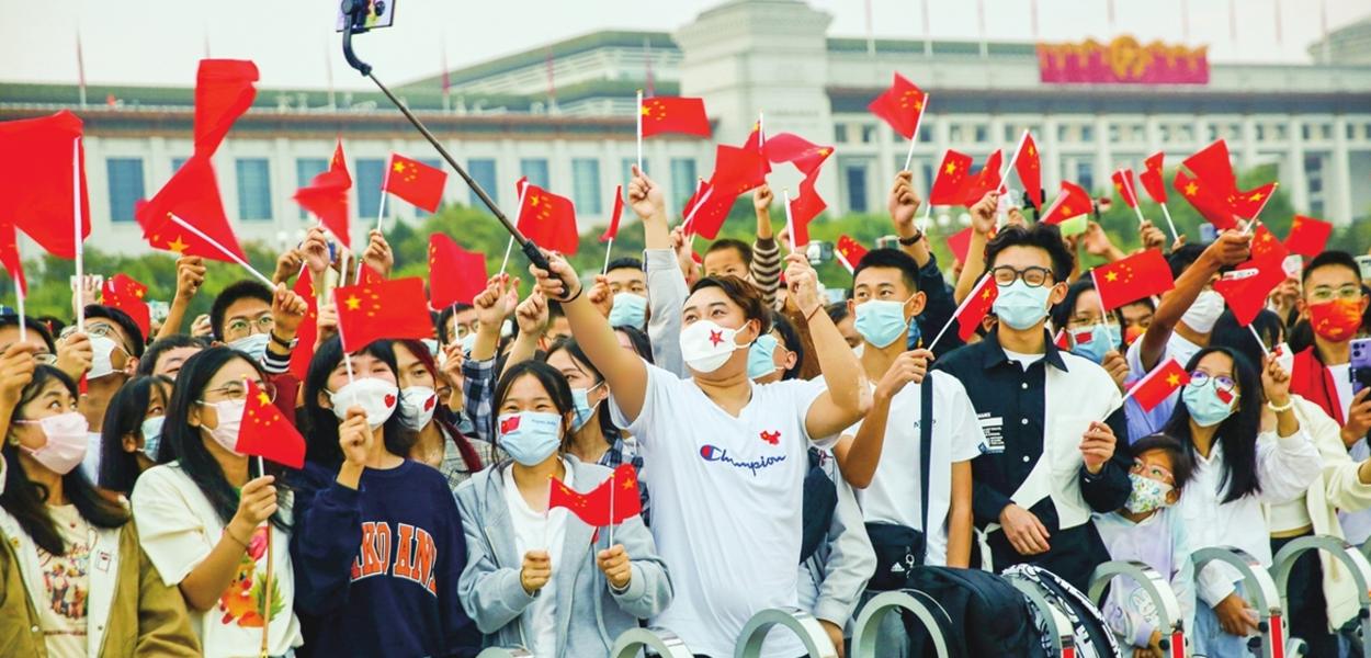 Patriotas chineses favoráveis ao governo comunista em cerimônia de hasteamento da bandeira na Praça da Paz Celestial