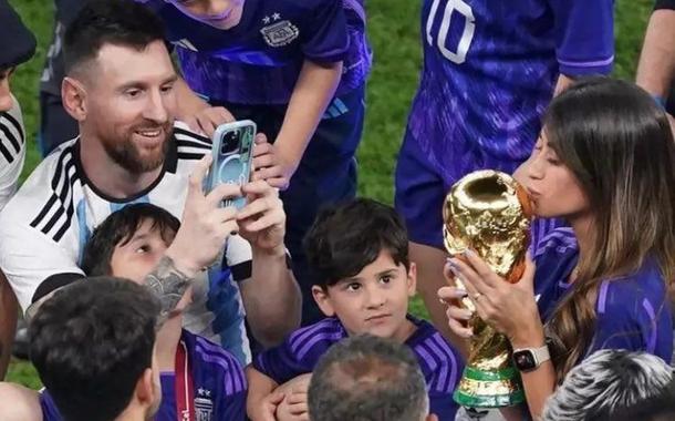 lionel Messoi (tirando foto com o celular) e Antonela Roccuzzo (com a mão na taça)