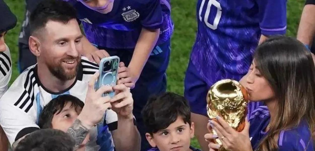 lionel Messoi (tirando foto com o celular) e Antonela Roccuzzo (com a mão na taça)